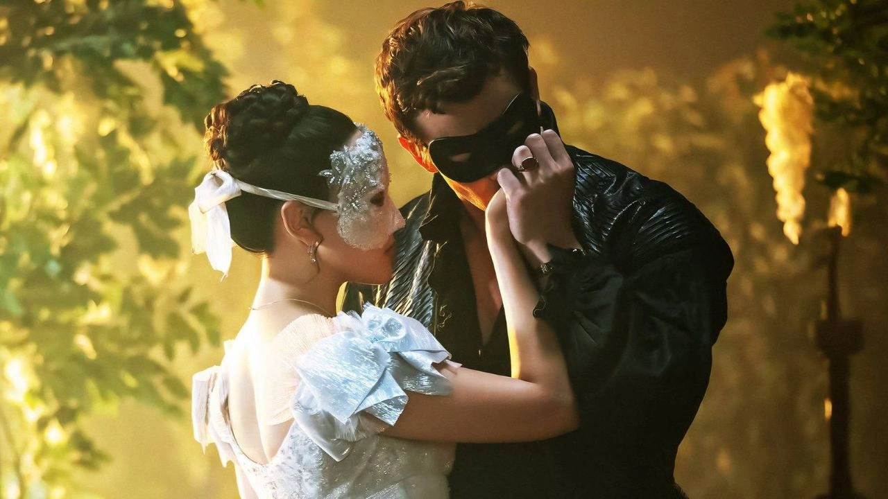 Benedict Bridgerton e Sophie Baek em um baile de máscaras, com luz de velas e clima romântico, enquanto ela usa uma máscara prateada. Benedict Bridgerton e Sophie Baek em um baile de máscaras, com luz de velas e clima romântico, enquanto ela usa uma máscara prateada.