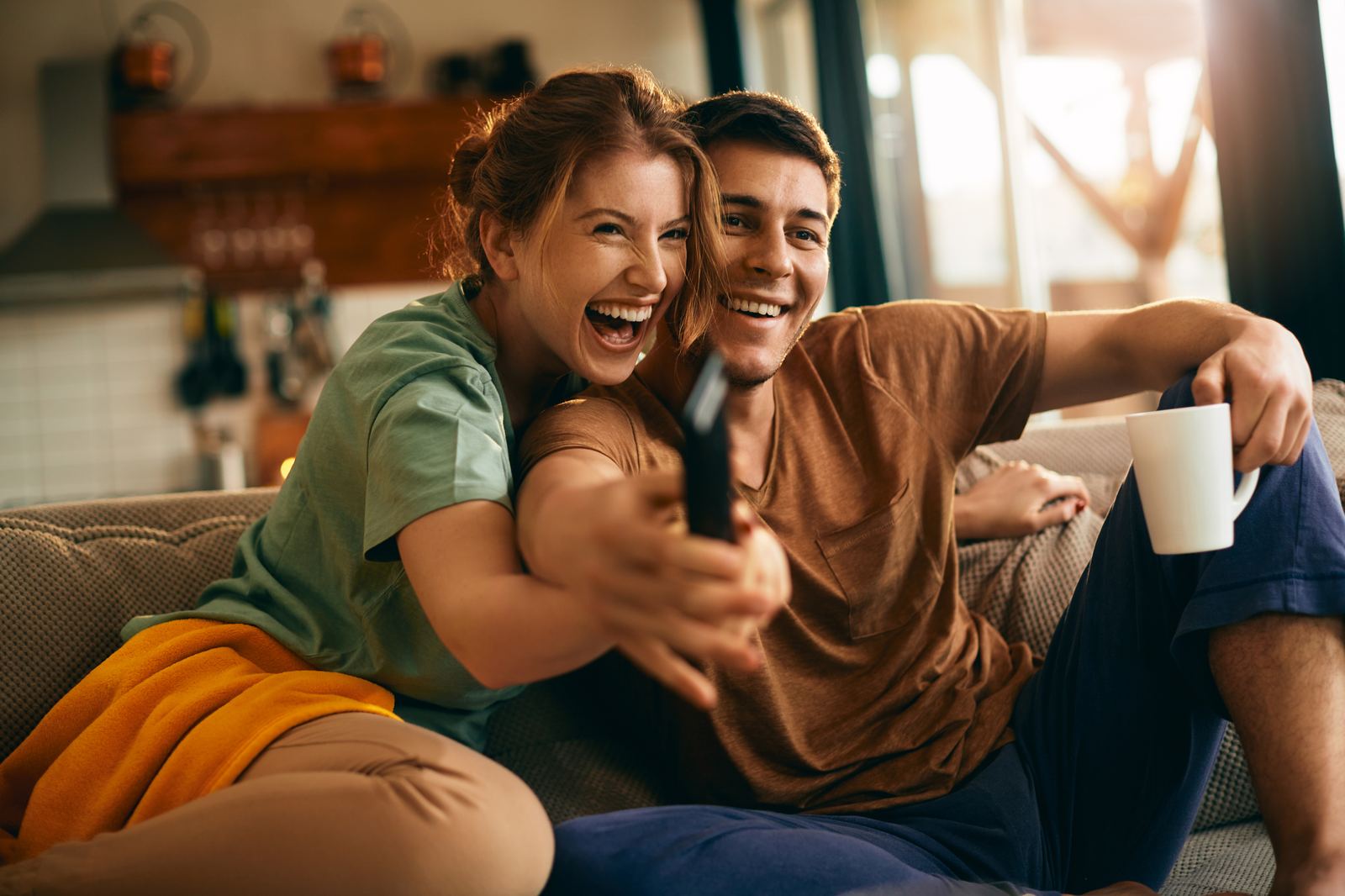 Casal usando o controle remoto para testar um serviço de streaming antes de assinar